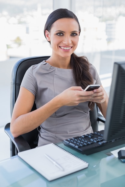 Alegre hermosa empresaria enviando mensajes de texto en su teléfono inteligente