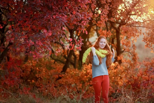 Alegre hermosa joven se encuentra en el bosque en una cálida bufanda sobre sus hombros