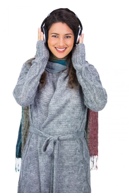Alegre hermosa modelo vistiendo ropa de invierno escuchando música