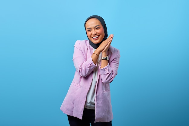 Alegre hermosa mujer asiática frotar las manos sobre fondo azul.