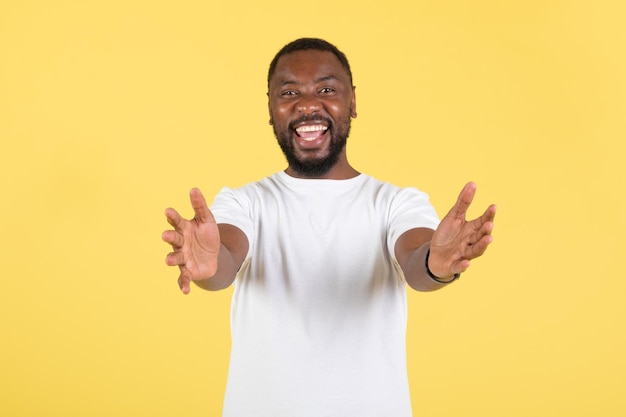 Alegre hombre africano estirando las manos a la cámara sobre fondo amarillo