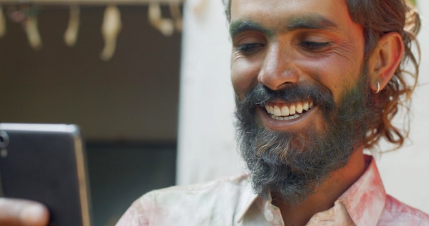 Un alegre hombre indio que tiene una videollamada asiste al festival Holi en India