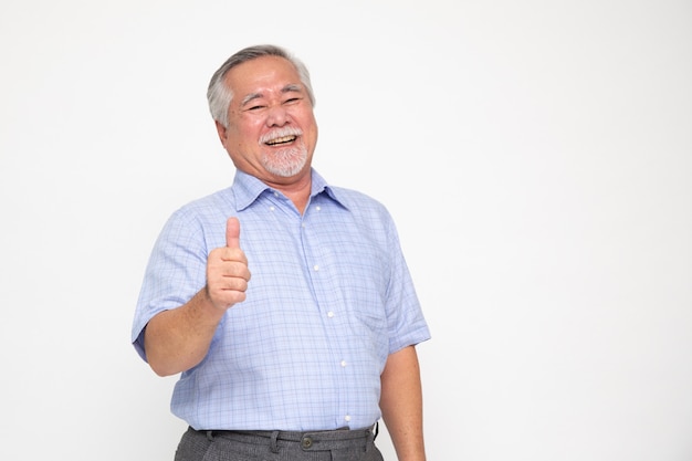 Alegre hombre senior asiático dando un pulgar hacia arriba y mirando a la cámara aislada en blanco