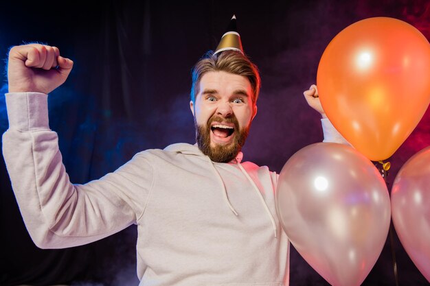 Alegre homem barbudo celebra algo feliz humor lúdico e vencedor levanta os punhos Hora da festa e conceito de férias