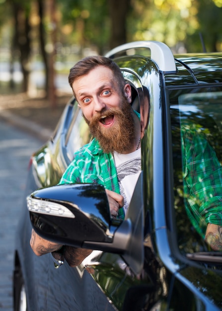 Alegre homem barbudo no carro.