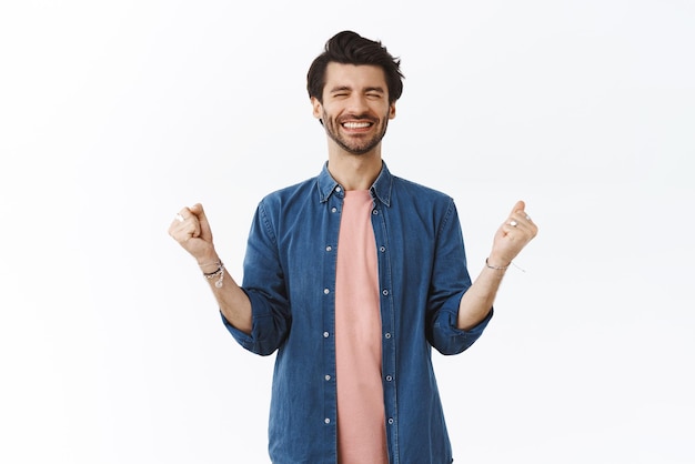 Alegre homem barbudo sortudo ganha muito dinheiro bomba de punho e celebrando notícias incríveis fecha os olhos e sorrindo aliviado finalmente sonho tornado realidade triunfando como alcançar o sucesso fundo branco