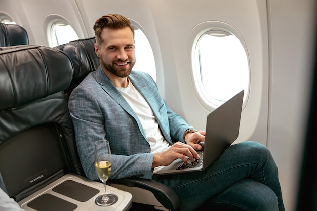 Alegre homem barbudo usando laptop no avião