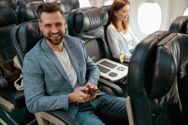 Alegre homem barbudo usando telefone celular no avião