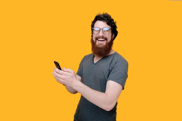 Alegre homem barbudo usando um celular em amarelo