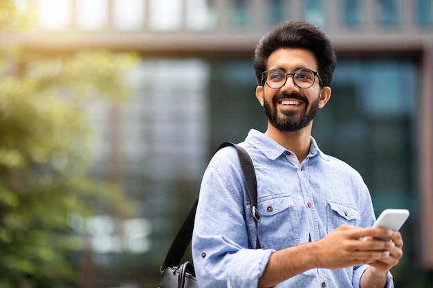 Alegre homem do milênio oriental, gerente de TI usando telefone celular