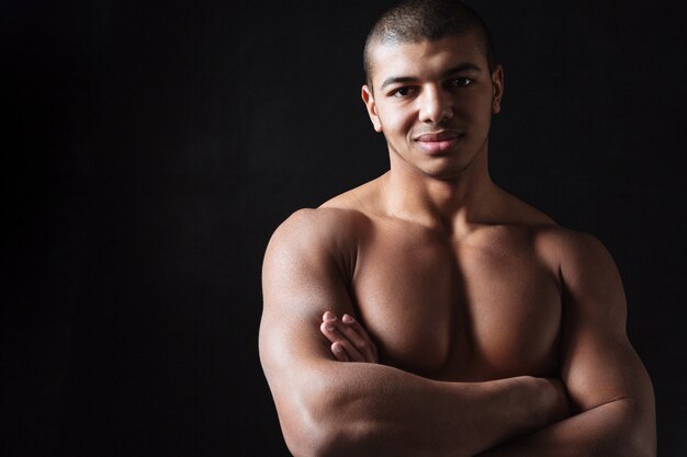 Foto alegre jovem desportista africana em pé com os braços cruzados