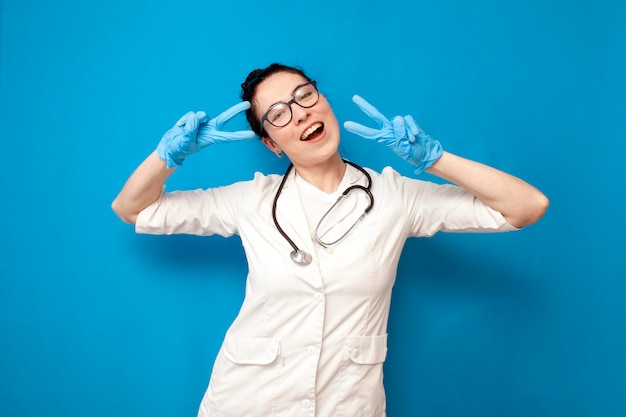 alegre jovem médica de uniforme posando para a câmera em fundo azul enfermeira feminina