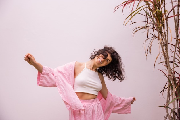 Alegre jovem morena caucasiana em roupas casuais acena o cabelo dançando no fundo branco conceito de estilo de vida de humor