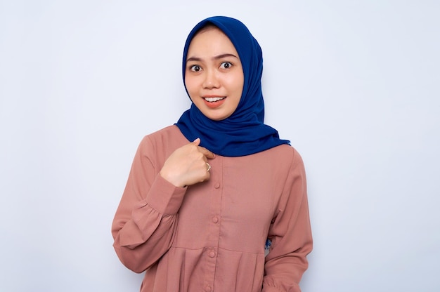 Alegre jovem muçulmana asiática na camisa rosa apontando os dedos para si mesma isolada sobre fundo branco Pessoas conceito de estilo de vida religioso