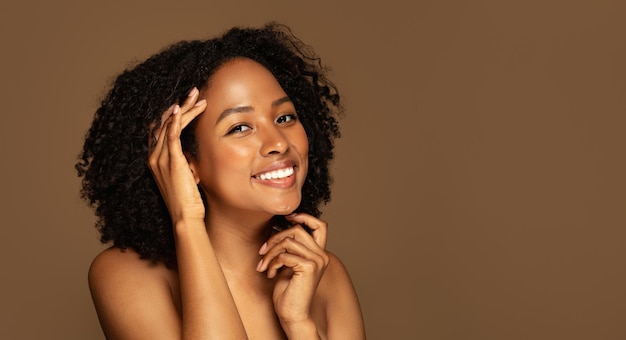 Foto alegre jovem negra posando de topless no panorama de fundo marrom