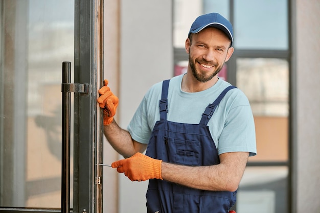 Alegre jovem reparando a porta no prédio