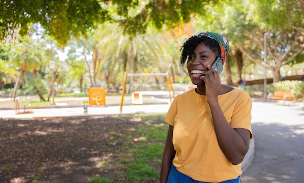 Alegre joven afroamericana hablando por teléfono móvil