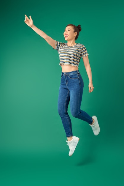 alegre joven asiática o adolescente saltando en el aire sobre verde.