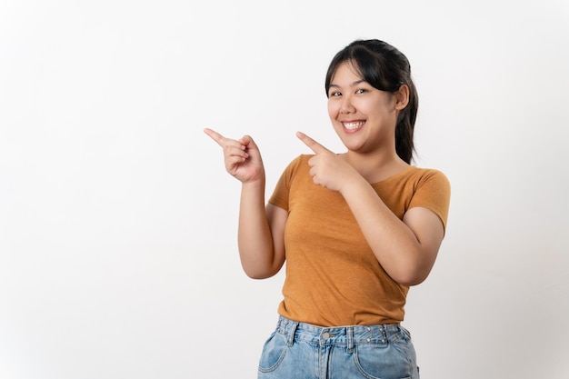 Foto alegre joven asiática tiene un gran pensamiento encontrar inspiración señalando con el dedo hacia arriba