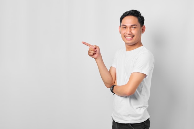 Alegre joven asiático señalando con el dedo el banner publicitario del espacio de copia aislado en el fondo blanco