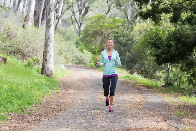 Alegre joven corriendo en el bosque