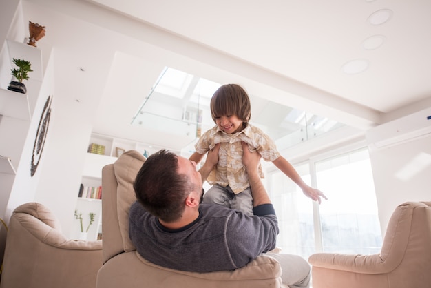 Alegre joven divirtiéndose con el padre en el sofá