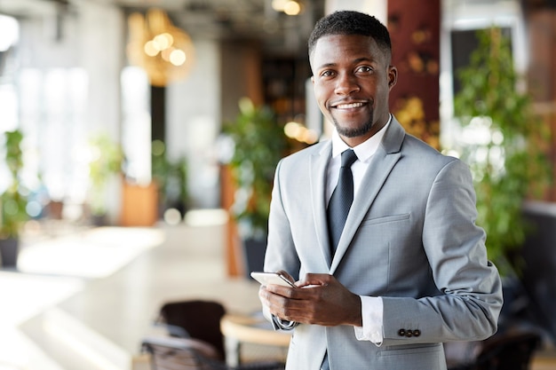 Foto alegre joven empresario afroamericano con smartphone