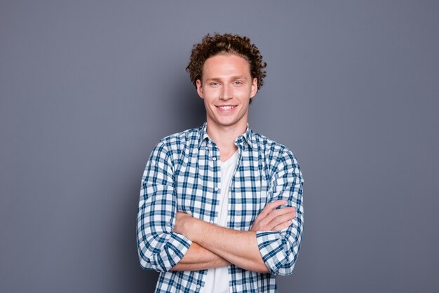 Alegre joven guapo en camisa a cuadros casual brazos cruzados