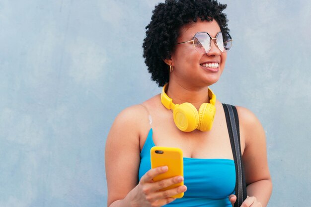 Alegre joven hispana sosteniendo el teléfono al aire libre