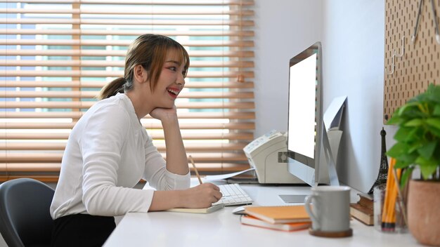 Alegre joven independiente que trabaja en línea desde casa revisando el correo electrónico comercial en la computadora