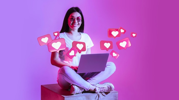 Foto alegre joven japonesa con gafas tiene una charla romántica con corazones en la computadora