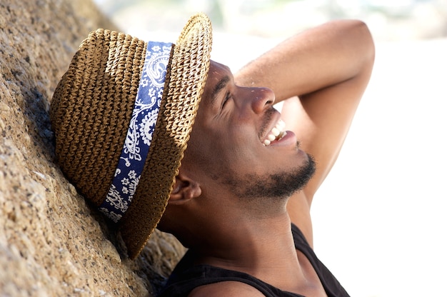 Alegre joven riéndose de la playa con sombrero