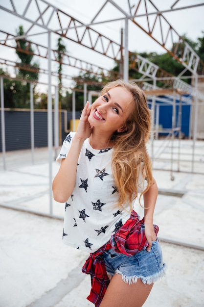 Alegre joven rubia posando al aire libre