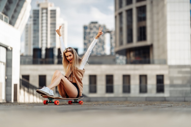 Alegre joven sentada en una patineta. Foto de alta calidad