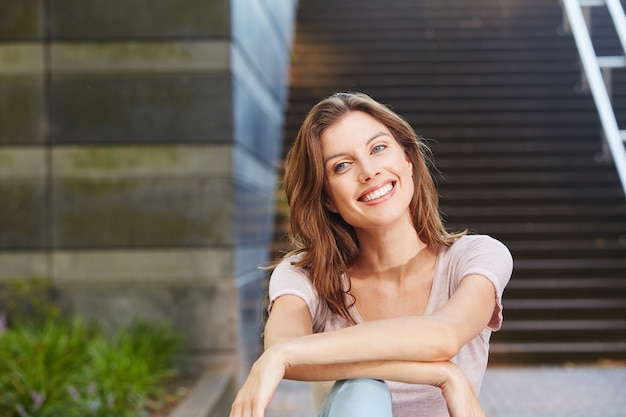 Alegre joven sentado al aire libre y sonriente