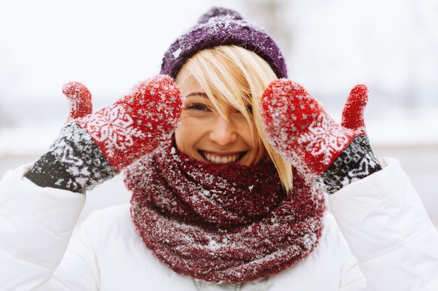 Alegre joven si sonriendo a la cámara y mostrando sus guantes, ambiente divertido de invierno.