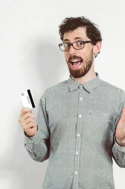 Alegre joven sosteniendo una tarjeta de crédito en la mano.