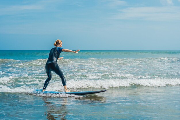 Alegre joven surfista principiante con surf azul se divierte en pequeñas olas del mar Estilo de vida familiar activo Gente lección de deportes acuáticos al aire libre y actividad de natación en el campamento de surf vacaciones de verano