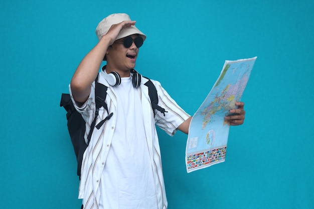 Alegre joven viajero turista con ropa informal de verano y sombrero con mapa. Pasajero que viaja ab