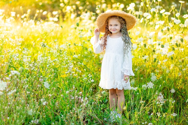 alegre linda garota com um chapéu de palha no verão em um campo amarelo com flores