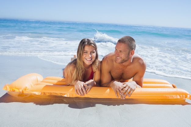 Alegre linda pareja en traje de baño acostado en la playa