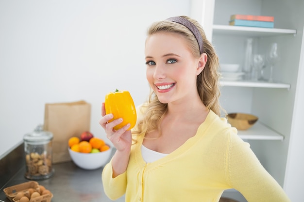 Alegre linda rubia sosteniendo un pimiento amarillo