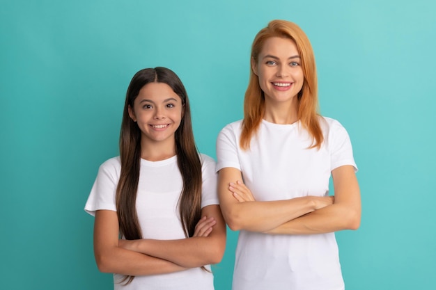 Alegre madre e hija con cabello lacio en camisas blancas manos cruzadas confianza