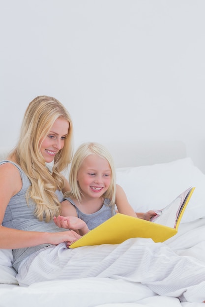 Alegre madre e hija leyendo una historia juntos