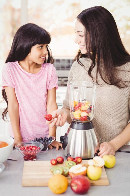 Alegre madre e hija preparando zumo de fruta