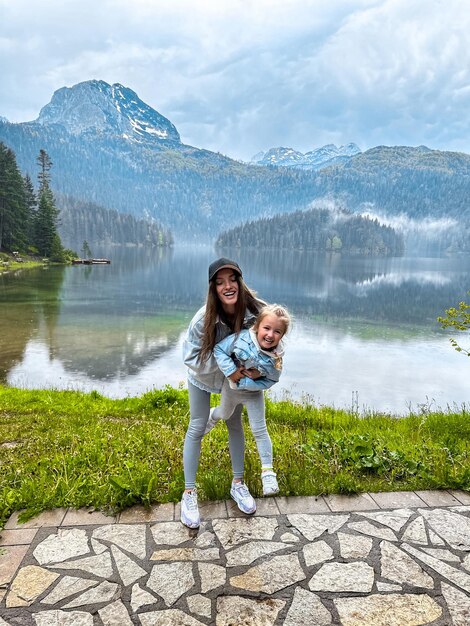 Foto alegre madre con hija en el hermoso lago de montenegro