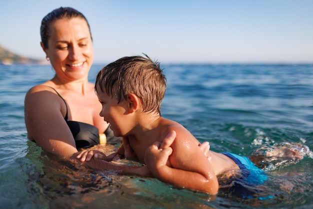 Alegre mãe brinca com seu filho no mar