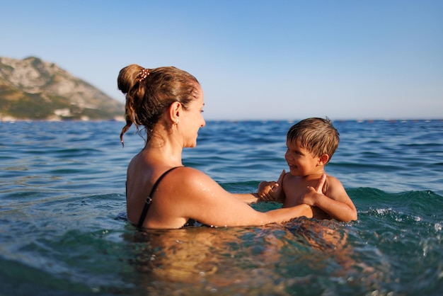 Alegre mãe brinca com seu filho no mar