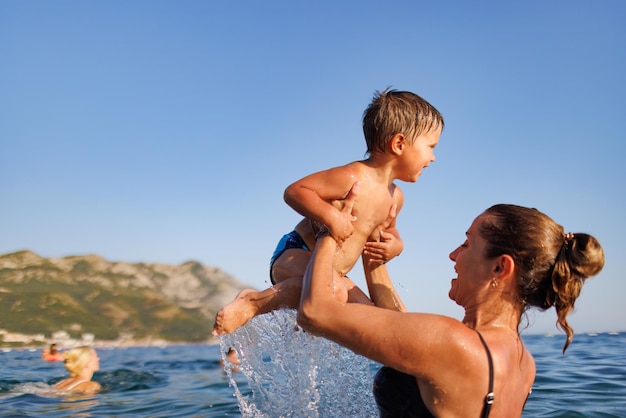 Alegre mãe brinca com seu filho no mar