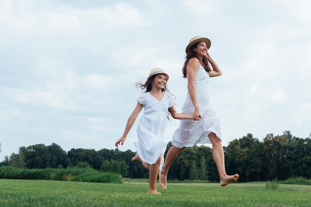 Foto alegre mãe e filha caminhando na natureza